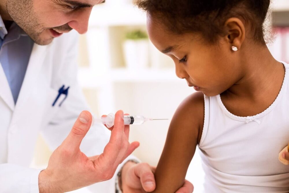 Doctor injecting vaccine to cute african girl